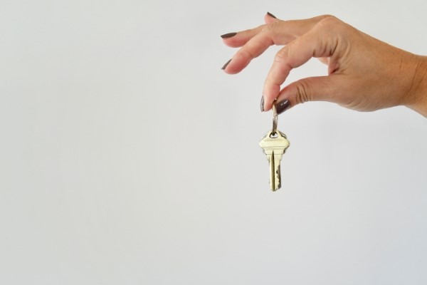 Mano sosteniendo llaves en oficinas inmobiliarias, representando el éxito de una transacción segura con Franquicias Alfa, expertos en bienes raíces de confianza.