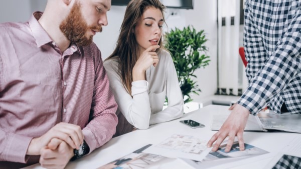 Pareja asesorada en oficinas inmobiliarias, disfrutando del servicio personalizado y orientación experta que ofrece Franquicias Alfa para cumplir sus sueños.
