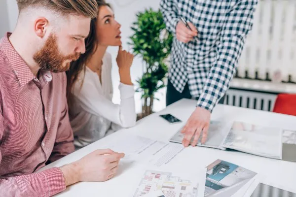 Pareja en una agencia consultando con asesores inmobiliarios expertos en la compra de inmuebles