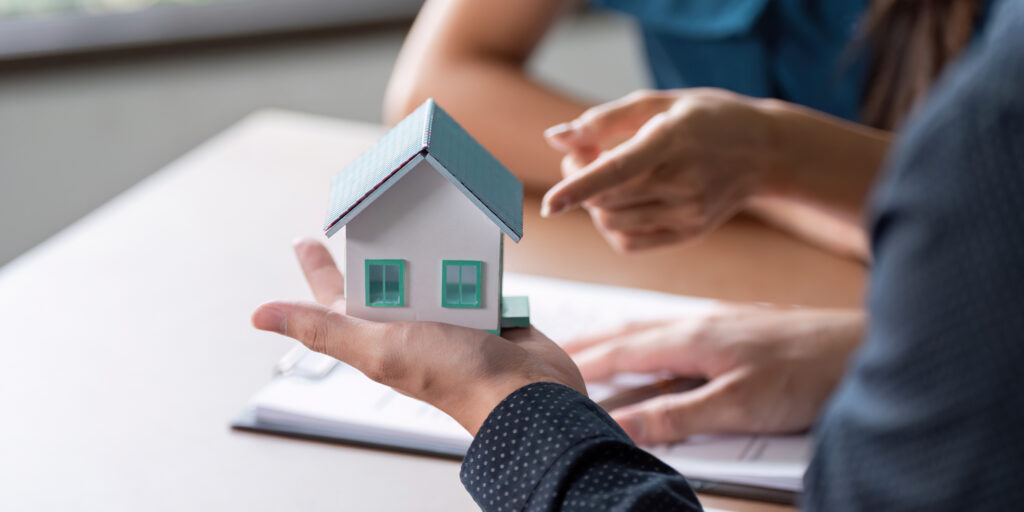 Consultoría inmobiliaria entre un agente y clientes en una oficina, revisando los detalles de la propiedad, destacando la profesionalidad de expertos inmobiliarios.