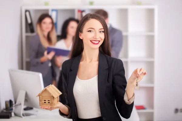 Retrato de un agente inmobiliario acompañando a una familia que recibe las llaves de su nuevo hogar, representando el papel de expertos inmobiliarios en su éxito.
