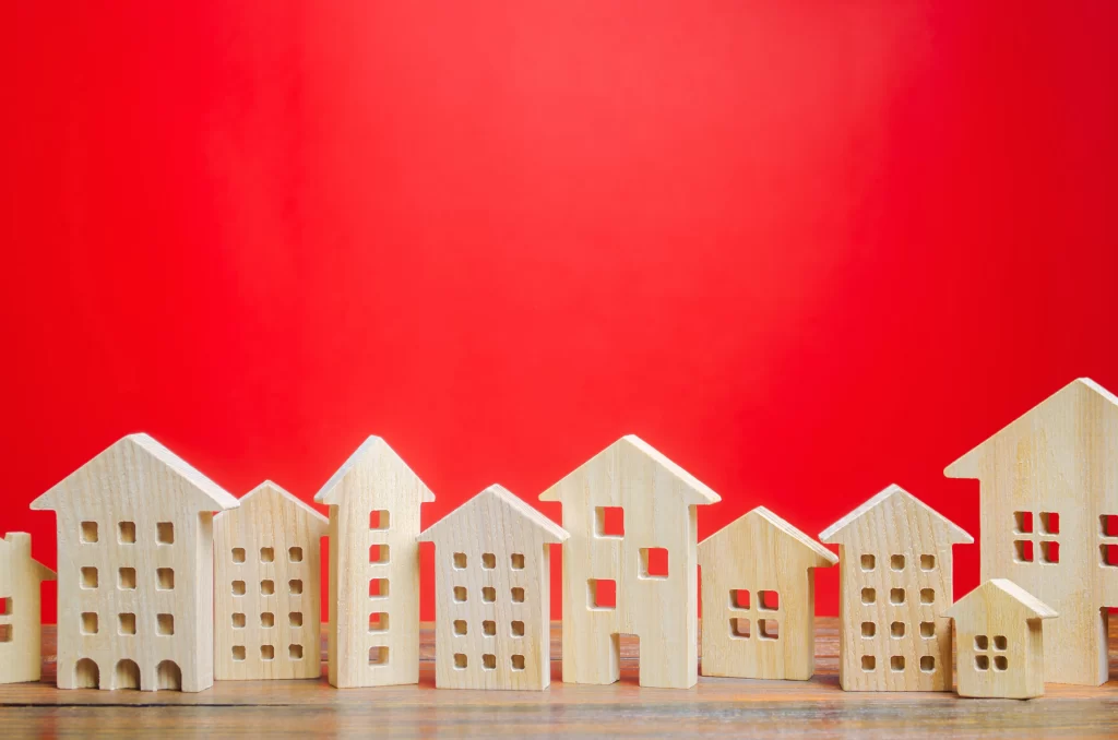 Casas de madera pequeñas sobre un fondo rojo, hacen referencia a zonas con mayor crecimiento inmobiliario en México
