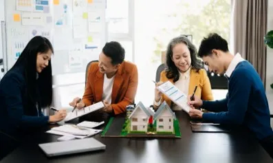 Equipo reunido viendo planos de casa. Invertir en inmuebles o en una franquicia inmobiliaria: ¿Qué conviene más?