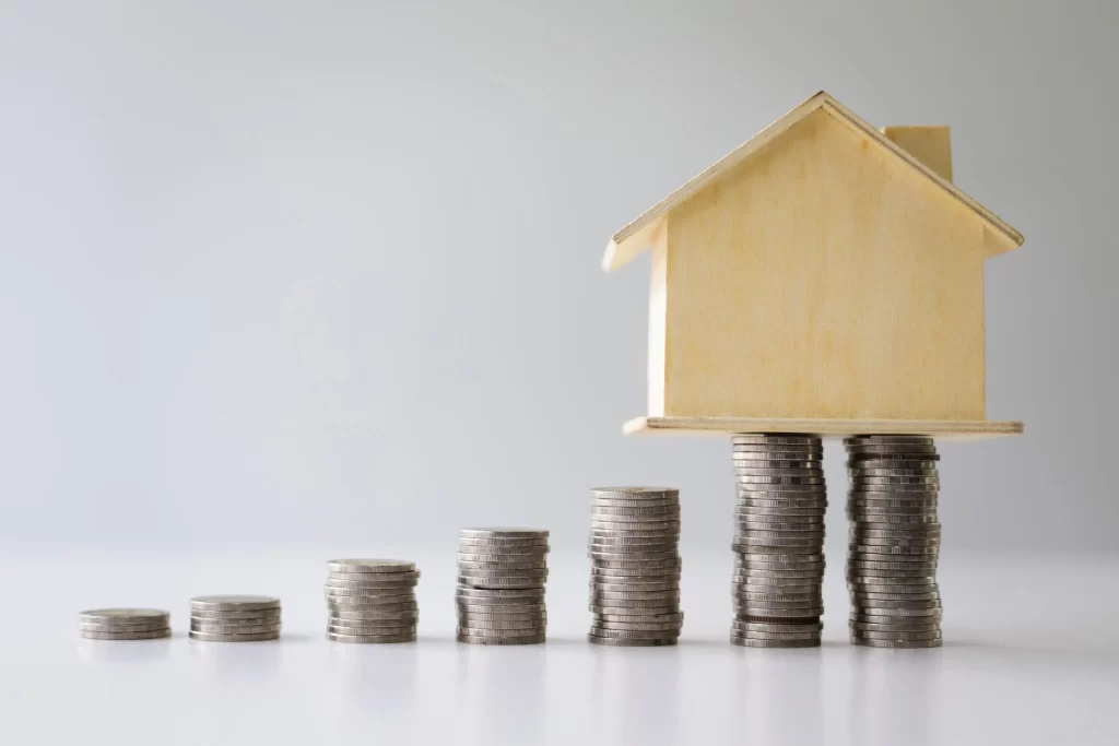 Pilas de monedas sosteniendo una casa de madera simboliza el retorno de inversión en franquicias en México