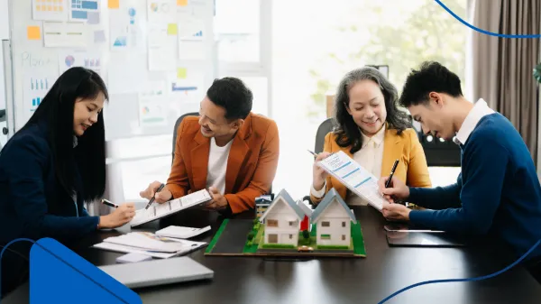 Mientras revisan planos y documentos junto a una maqueta de casas, este equipo analiza diversas posibilidades, lo cual es clave al momento de decidir dónde invertir en el sector inmobiliario.