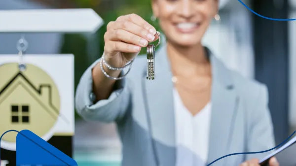 Una mujer sonriente entrega unas llaves frente a una propiedad, reflejando éxito que sí es rentable ser agente inmobiliario.