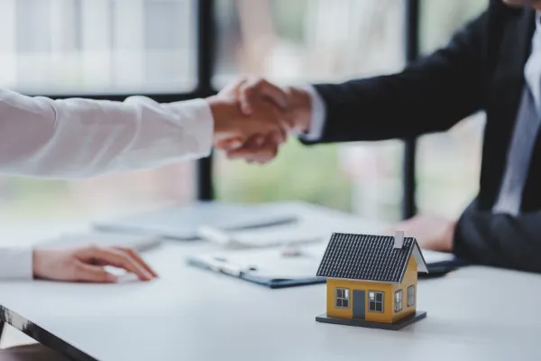 Dos personas se dan la mano, mostrando cómo trabajar en el sector inmobiliario implica negociar acuerdos y generar confianza con los clientes.