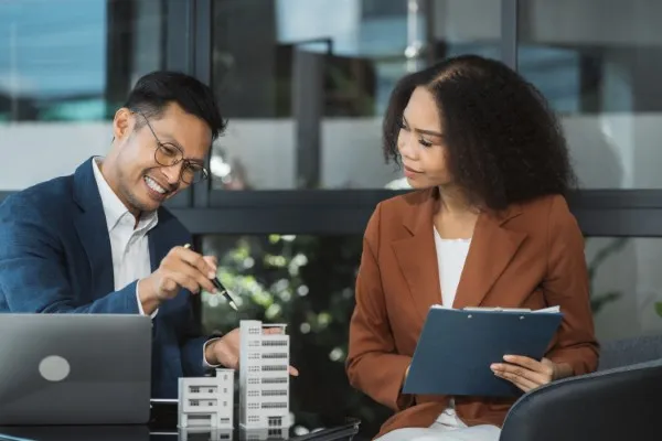 Un hombre y una mujer revisan una maqueta, mientras conversan en una oficina, representando planificación y estrategia en los mejores negocios en México.
