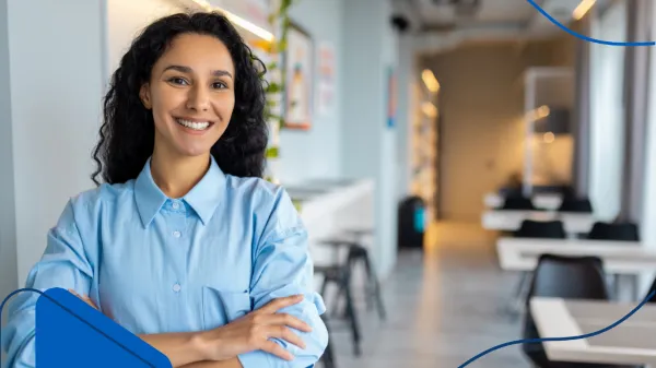 Una mujer sonriente de pie en una oficina moderna representa a quienes deciden invertir en franquicias como una alternativa profesional en crecimiento.