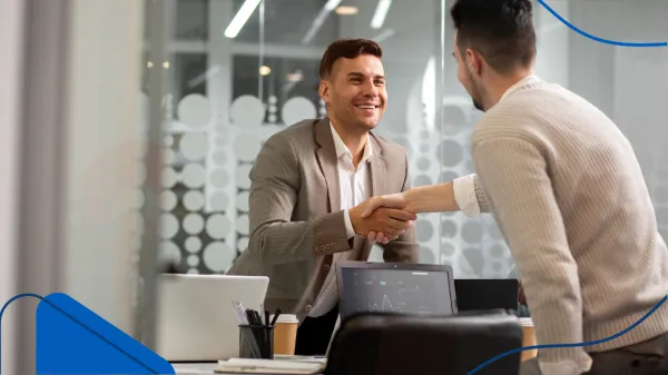 Dos personas se dan la mano al cerrar un trato en una oficina moderna, un gesto común al definir qué se necesita para tener una franquicia exitosa.