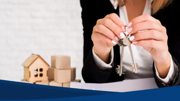 Una mujer sostiene un juego de llaves frente a un cliente, gesto típico del trabajo de asesores inmobiliarios al formalizar la entrega de una propiedad.