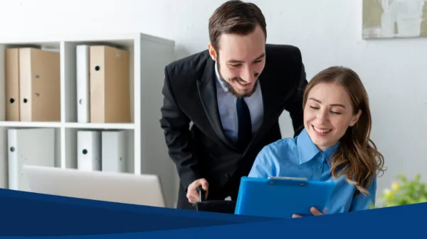 Un asesor revisa documentos junto a una mujer que sonríe mientras sostiene una tableta, transmitiendo la confianza que acompaña a un negocio seguro.
