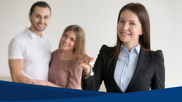 Una agente sonríe mientras entrega unas llaves a una pareja, mostrando el acompañamiento que brindan los profesionales inmobiliarios.